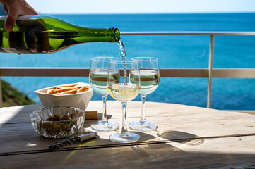 Pouring in glasses of txakoli or chacolí slightly sparkling very dry white wine produced in the...
