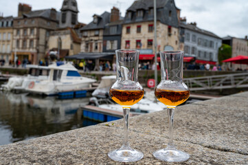 Tasting of apple calvados drink in old Honfleur harbour with boats and old houses on background, Normandy, France