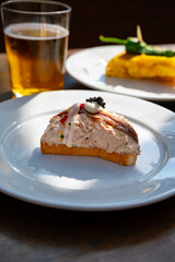 Sunny day in San Sebastián, typical food and drink in bars of Basque Country, pinchos or pinxtos, small slices of bread with different toppings and glass of beer, lunch in Spain
