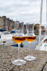 Tasting of apple calvados drink in old Honfleur harbour with boats and old houses on background, Normandy, France