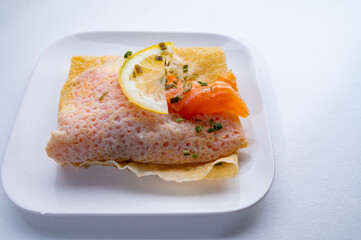 Cuisine of Normandy, galette pancake filled with goat cheese and smoked salmon served with fresh lemon