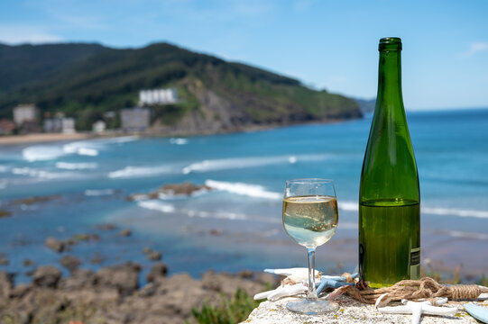 Txakoli or chacolí slightly sparkling very dry white wine produced in the Spanish Basque Country, served outdoor with view on Bay of Biscay, Atlantic Ocean.