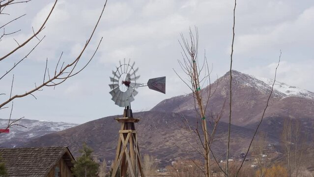 Windmill blowing in the breeze looking towards mountain on cloudy day.