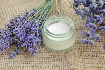 Open jar of lavender moisturizer. Jar of body cream and fresh lavender flowers