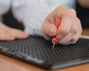 A woman uses a special stencil and stylus to write a letter in braille. 