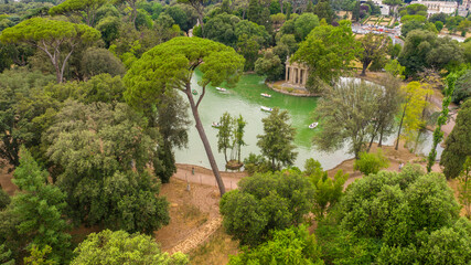 Fototapeta na wymiar Aerial view of the small lake in Villa Borghese park. This pond is located in Rome, Italy. There are small row boats with people.