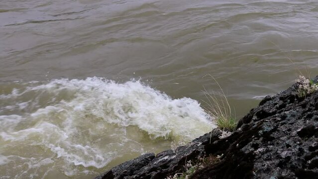 Spring mountain river beats against stones with white foam. 