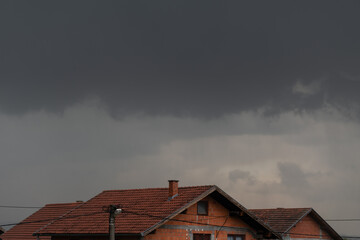 Dark clouds hovered over the roofs, storm clouds in suburb