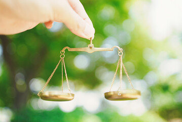 天秤を持つ男性の手元と緑ぼかし背景