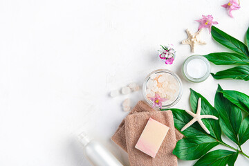 Spa elements, towel, soap, salt, cream and flowers on a white background. Top view, copy space.
