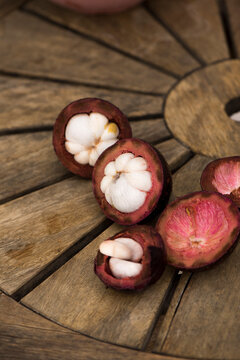 Mangosteen on rustic wooden table, Fresh ripe fruits and cross section  is known as "The Queen of Fruits"