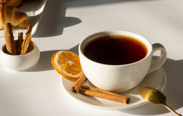 tea in the white mug or cup on a white, light background with fresh pastries and croissants, breakfast or morning concept