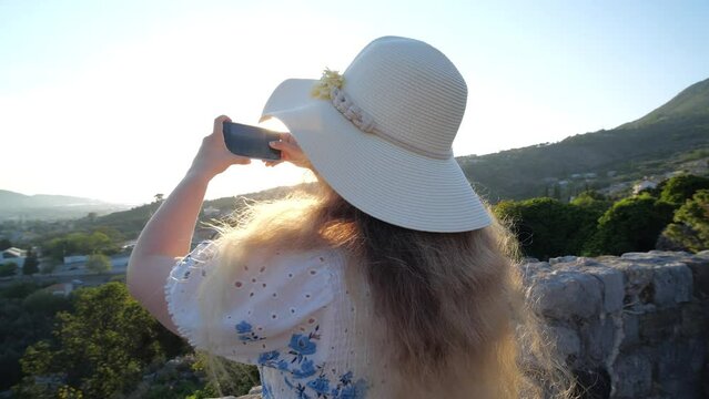 Tourism and travel concept. Woman wearing a hat and a red using her mobile to take photos in a old town