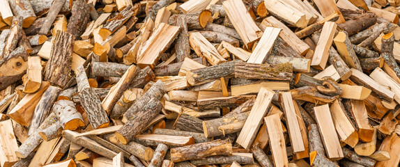 A pile of stacked firewood, prepared for heating the house. Firewood for ready heating in winter.Chopped firewood.environment background.Banner,advertisement.