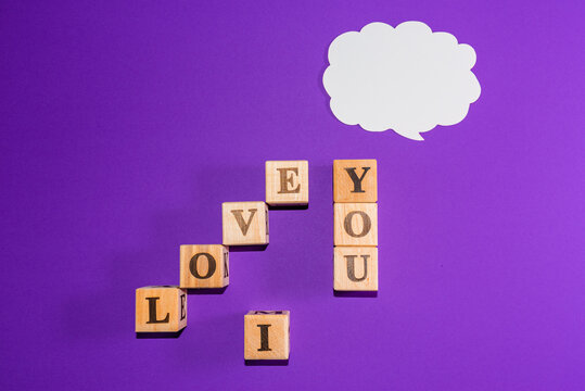 Message I love you spelled in wooden blocks with cloud. copy space,indoors shot.Purple,veri peri background.