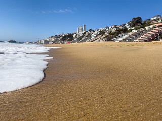 Wave foam on sand shore in Reñaca beach on sunny day. Popular tourism vacation destination city in Chile