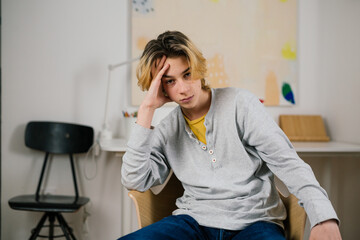 indisposed teenager boy sitting at home looking at camera