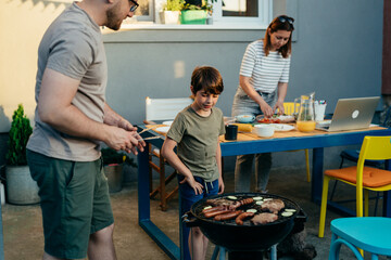 father and son preparing barbecue together in backyard