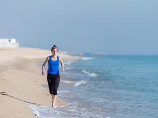 Front view of women jogging on beach close to water