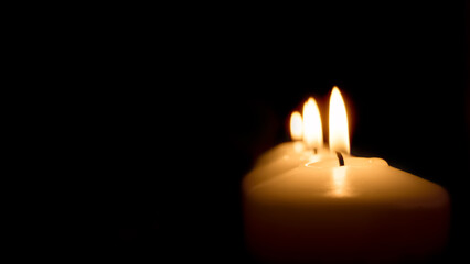 candles at night on a dark background, light and heat from the candle