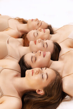Close-up portrait of beautiful women lying on floor head to head in mosaic style isolated over white studio background