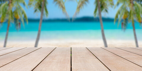 Fototapeta premium Empty old wooden table in front of blurred background of sea, sand, palm tree, mountain and tropical beach at summer vacation and travel concept with copy space.