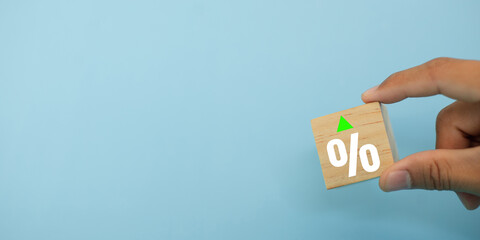 Financial crisis concept. Hand holding wooden block signs and symbols on blue background with percentage sign grow of income, capital lost, cost reduction, declining chart. down profit.