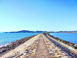 Fototapeta na wymiar 和歌山県の観光地、日本遺産和歌の浦にある片男波海水浴場の防波堤と青空と海の晴れた夏の日の爽快な風景（コピースペースあり）