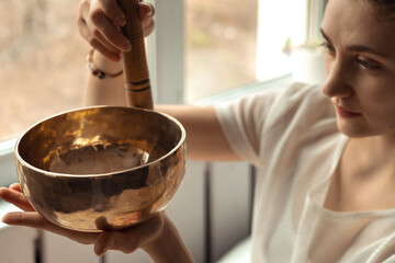 Young woman playing on a singing tibetian bowl.Relaxation and meditation.Sound therapy,alternative...