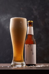 Bottle and glass of beer on black background.