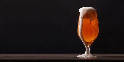 Tulip glass of beer on black background.