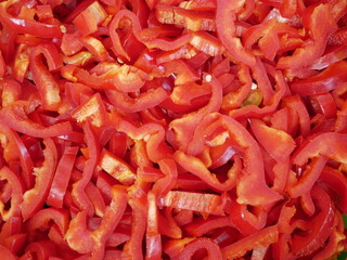 Thinly sliced red bell pepper on a plate. Fresh vegetables for salad. Natural vegetarian food, rich in vitamins.
