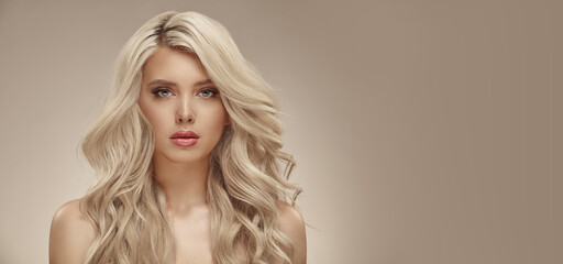Much attractive blonde woman with long healthy curly hair on beige isolated with free copy space - obrazy, fototapety, plakaty