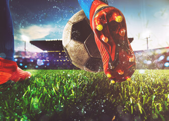 Football scene at night match with close up of a soccer shoe hitting the ball with power