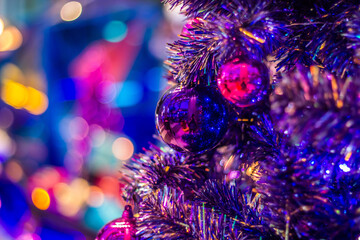 Christmas balls on colorful Christmas tree with blurred background.