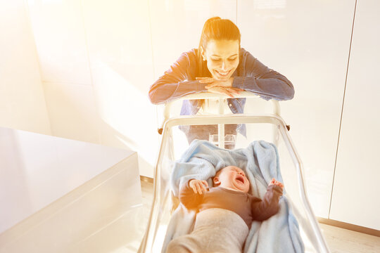 Mutter lächelt ihr weinendes Baby im Babybett an