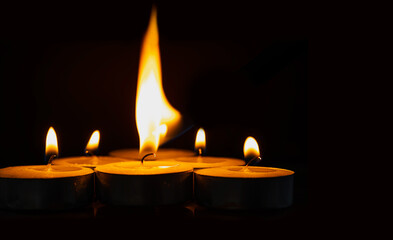 Burning candles isolated on dark surface background.
