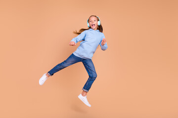 Fototapeta na wymiar Full size portrait of energetic active person jumping have fun enjoy listen music isolated on beige color background