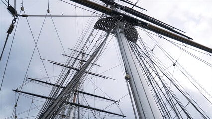 Close-up of the rigging and mast of Cutty Sark ship against the blue cloudy sky. Action. Greenwich,...