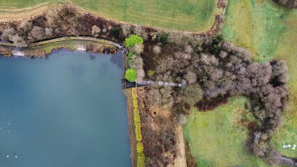 Aerial view looking down onto a lake surrounded by large trees. 