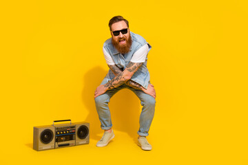 Naklejka premium Photo of pretty funny guy dressed denim vest rising dark glasses enjoying songs boombox dancing isolated yellow color background