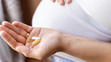 Healthcare, treatment, supplements. Happy smiling woman taking pill with supplement vitamin Omega 3. Pregnancy, medicine health care concept.