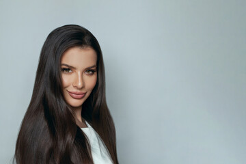 Obraz premium Beautiful woman face. Cheerful woman with clean skin and long healthy hair smiling on white background