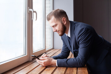 Fototapeta premium Businessman using smartphone and smiling. Young business executive with mobile phone portrait