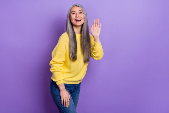 Photo of cute positive friendly lady go walk meet her best friend waving hands say hello isolated on purple color background