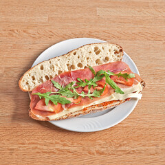 Plate with a Parma ham and cheese sandwich on wooden table