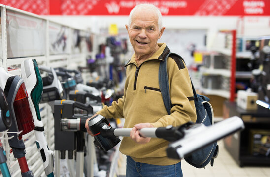 senor man pensioner buying Upright Vacuum Cleaner in showroom of electrical appliance store