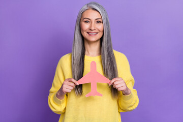 Photo of pretty shiny retired woman wear sweater holding ink paper aircraft isolated violet color background
