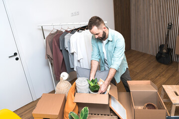 Hipster man with moving boxes in new modern apartment. Mature man unpacking things from boxes while moving in new apartment. 