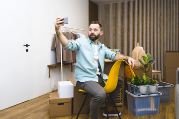 Hipster man with moving boxes in new modern apartment. Mature man using mobile phone while unpacking things from boxes moving in new apartment. 